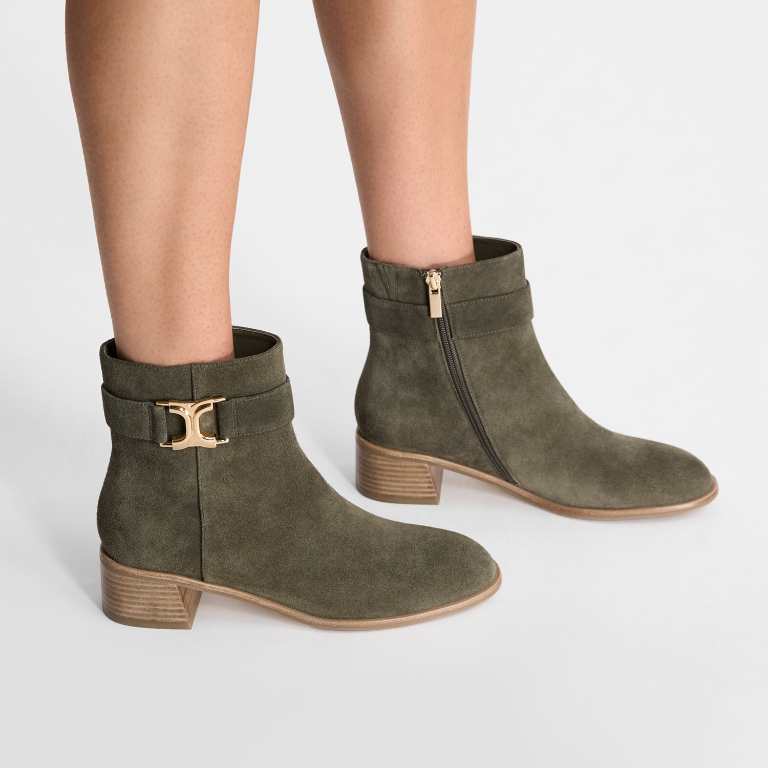 Green suede ankle boots with gold buckle on a white background