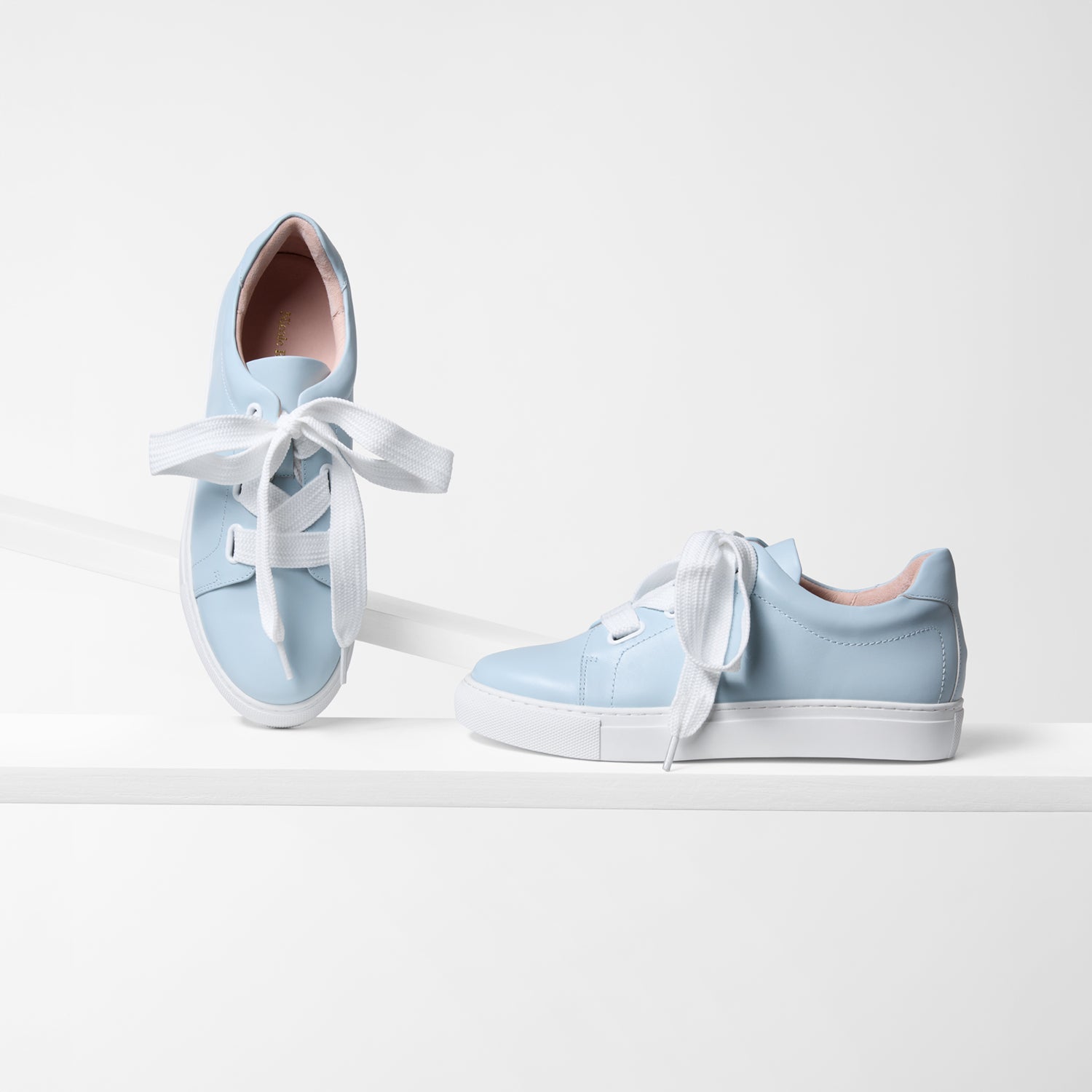 Light blue sneakers with white laces on a white background