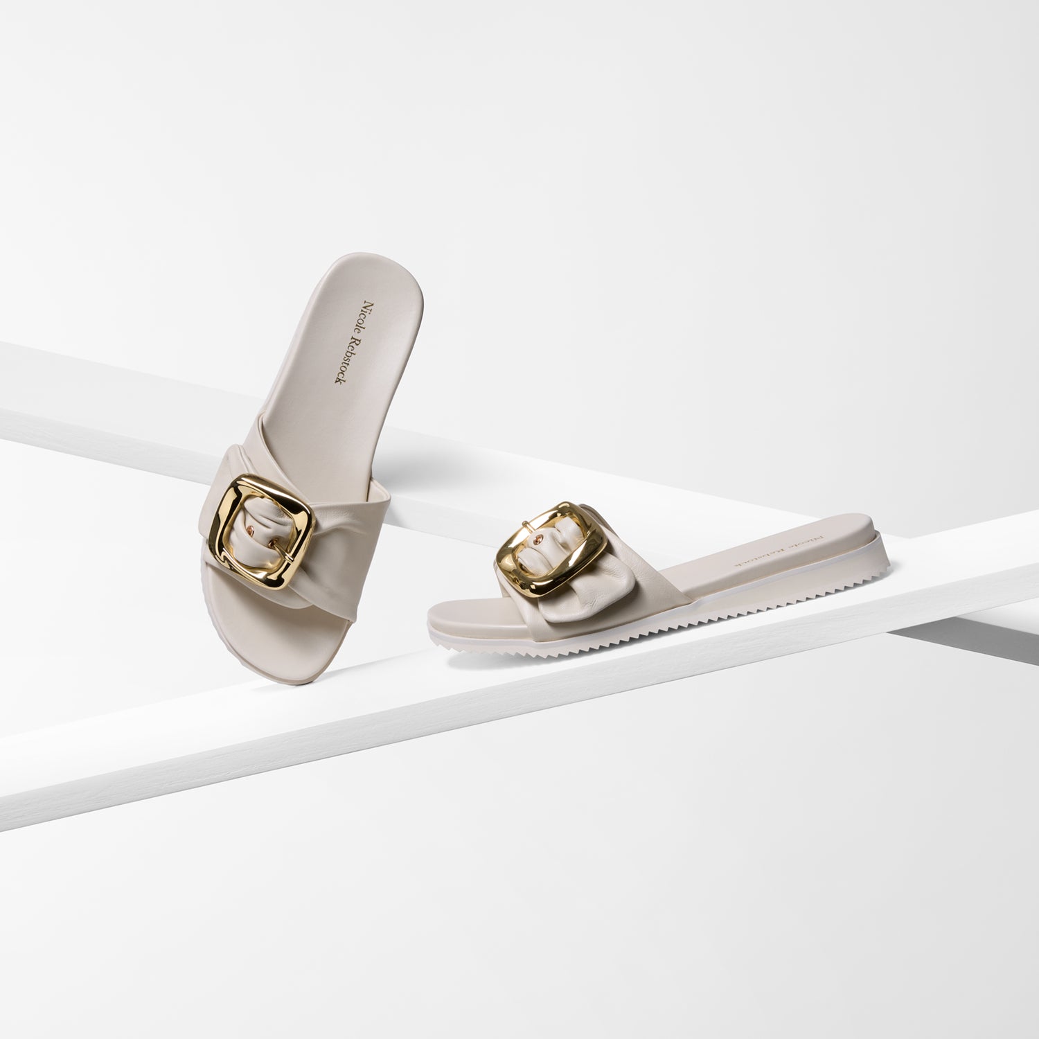 Ivory slides with gold buckles on a white background