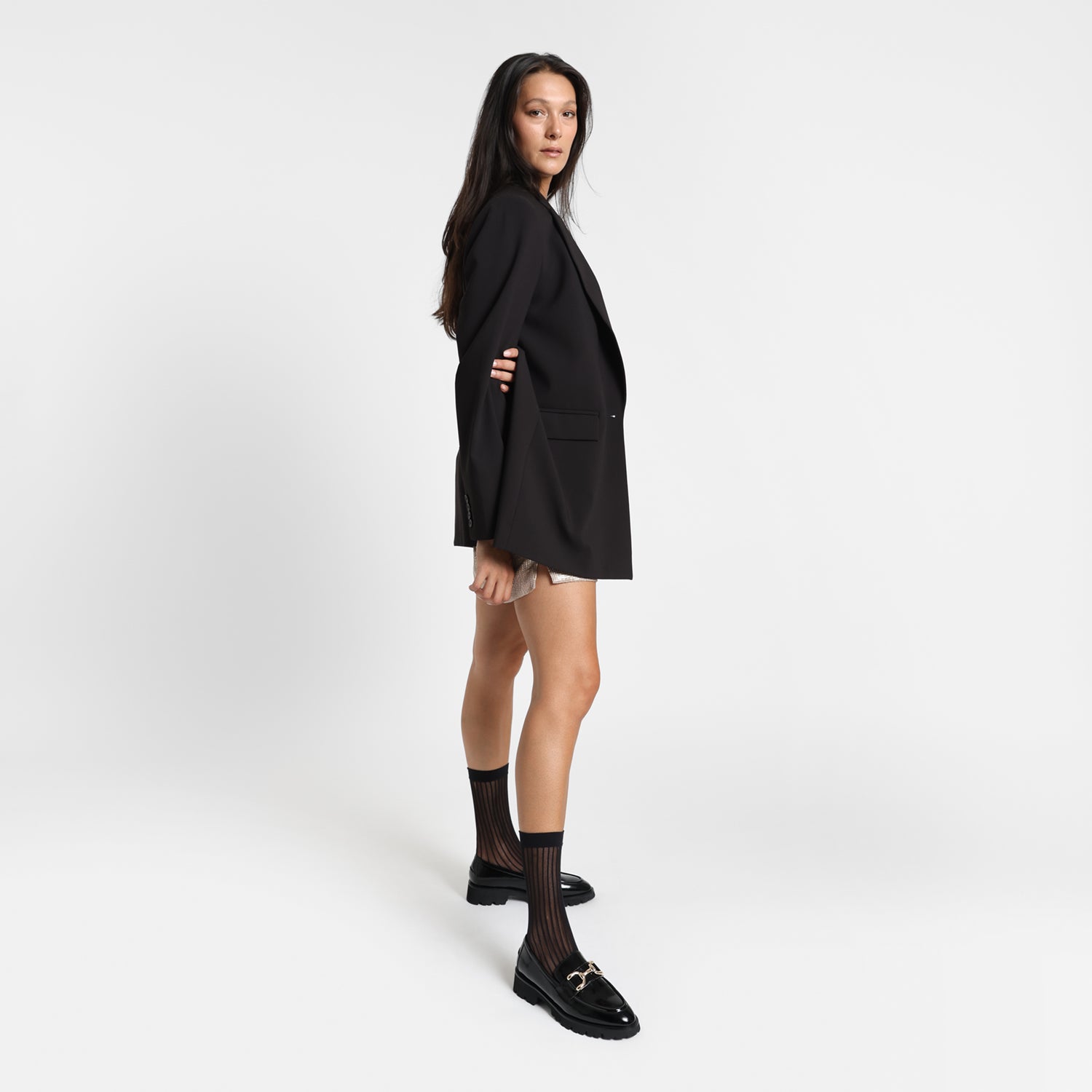 Women wears black oiled leather California Loafer shoe with black chunky outsole and gold buckle. 2.5cm heel.