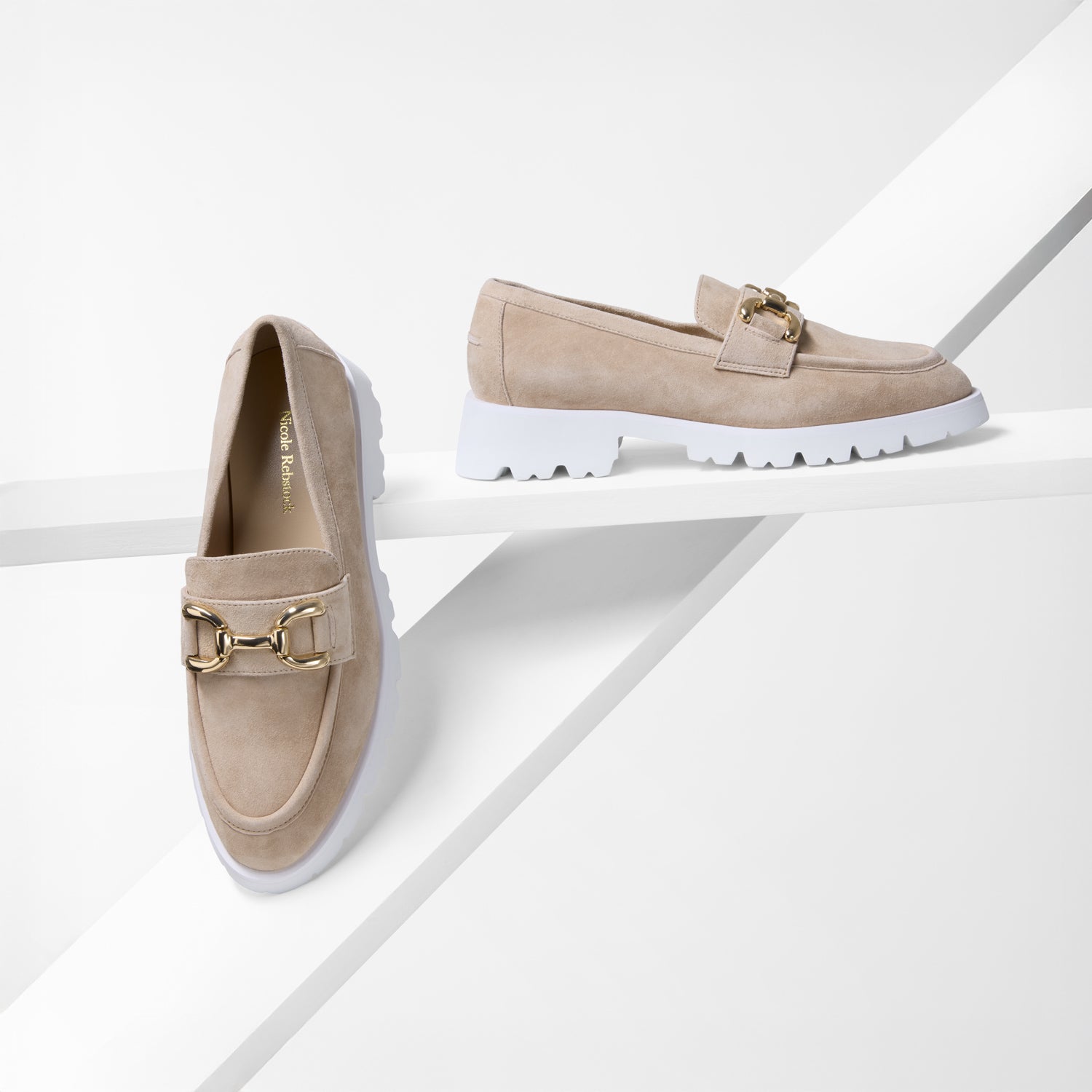 Pair of nude suede loafers with gold buckles on a white background by Nicole Rebstock