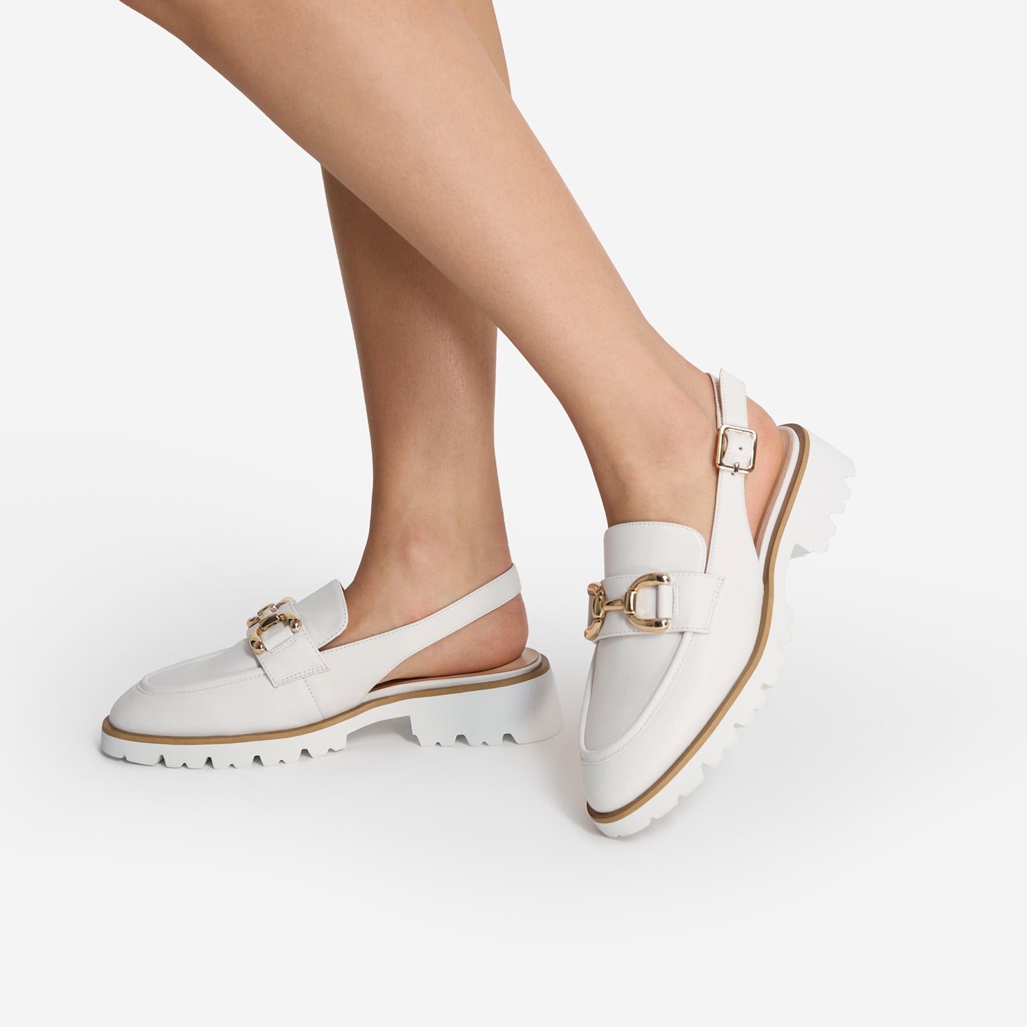 White slingback loafers  with gold accents by Nicole Rebstock worn by a person on a white background