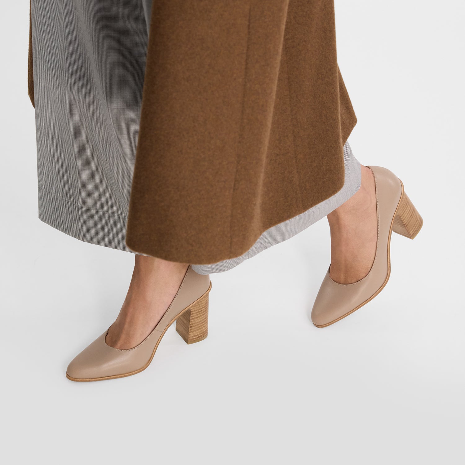 Beige Pumps worn with a brown skirt and gray pants on a white background