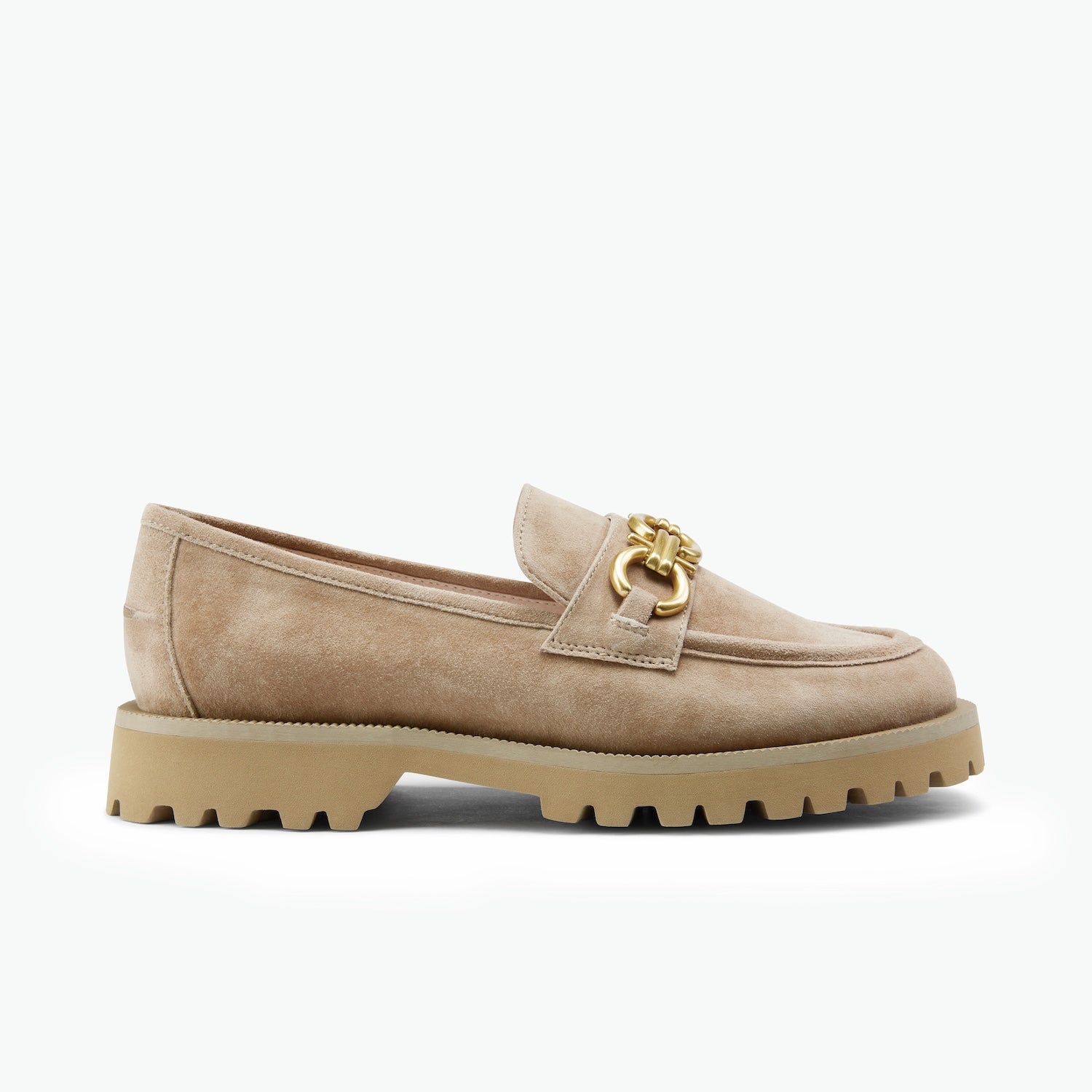 A single beige suede loafer with a chunky tan sole and a gold-tone horsebit detail on the strap, shown from the side against a plain white background.