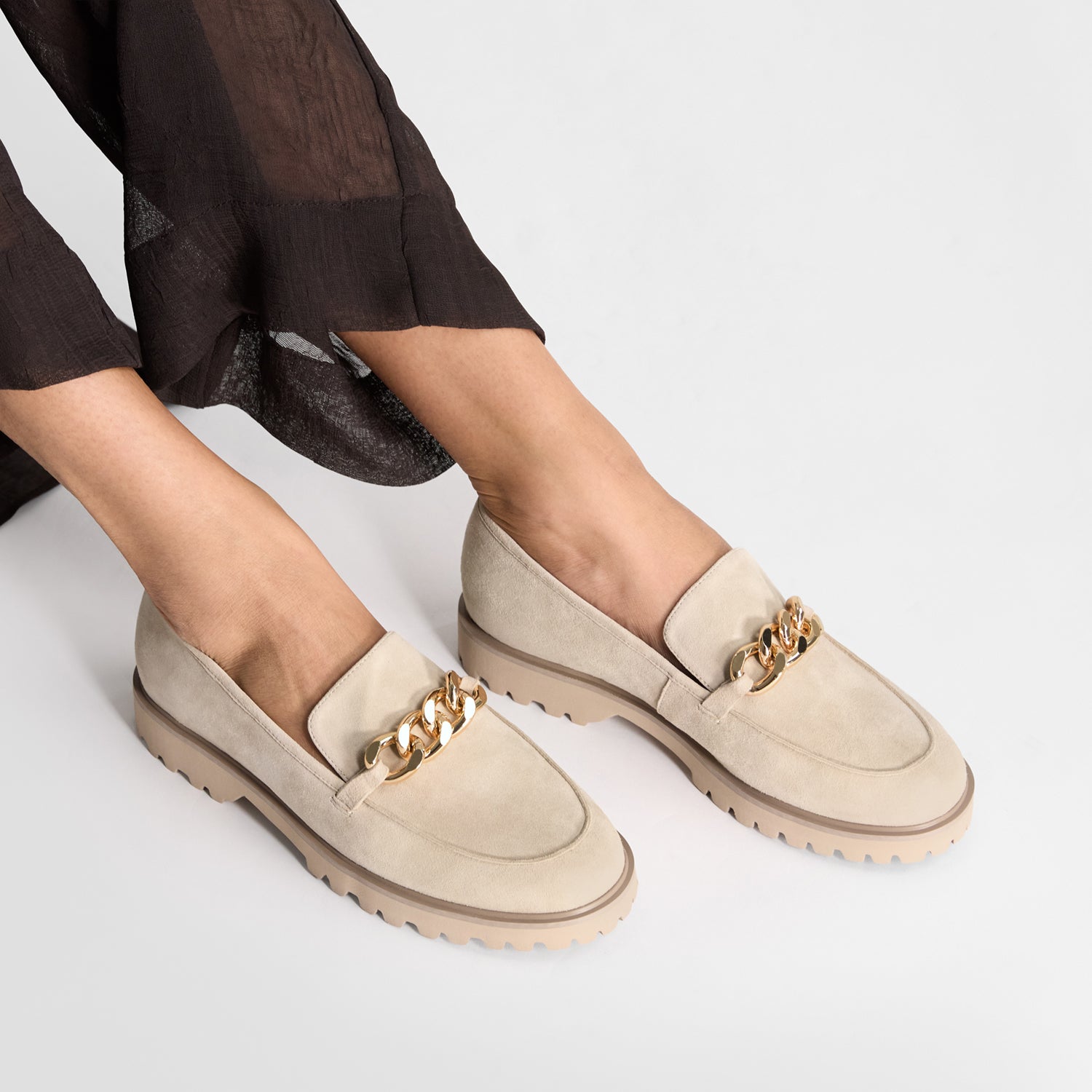 Nude suede loafer called Dominica worn on feet. Gold chain and chunky EVA sole. By Nicole Rebstock.