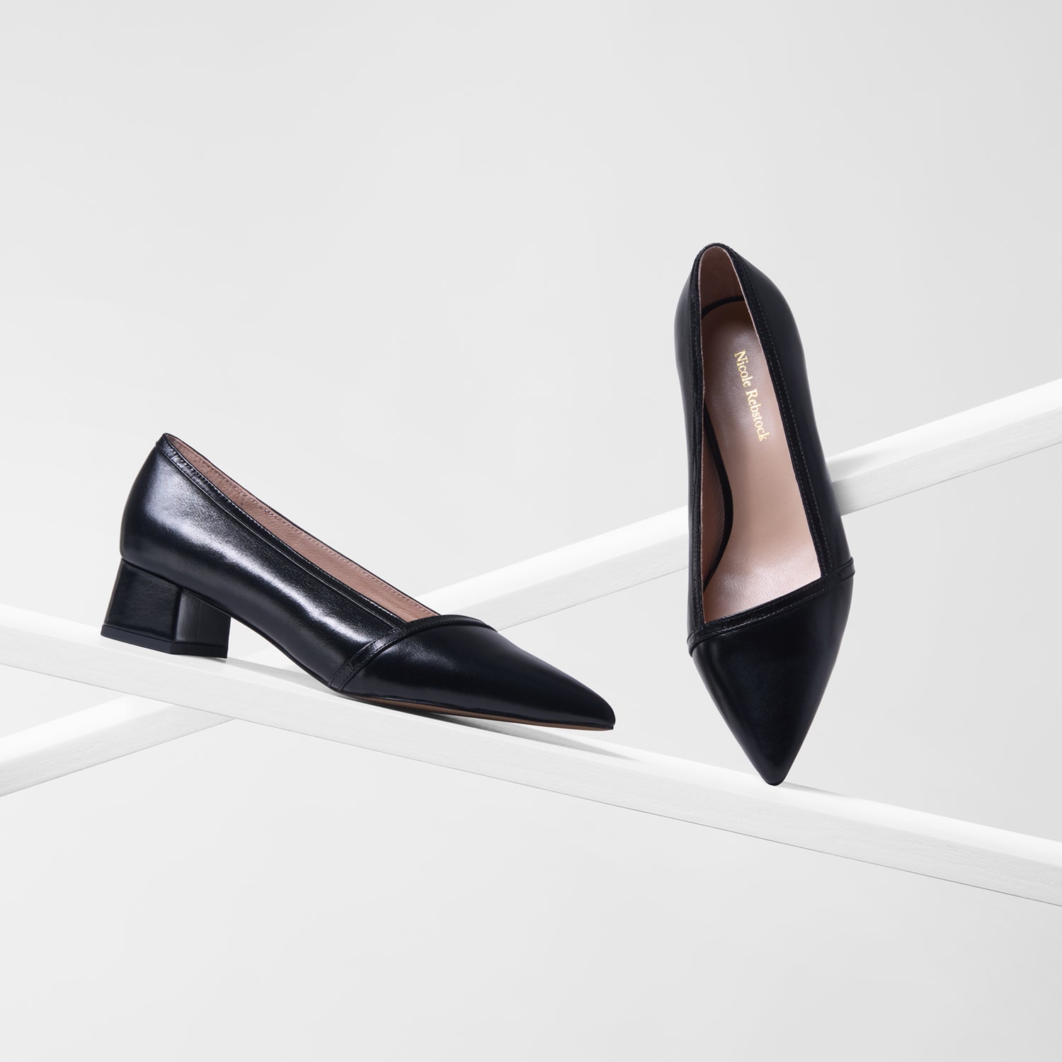 Black pointed-toe shoes on a white background with a low block heel.