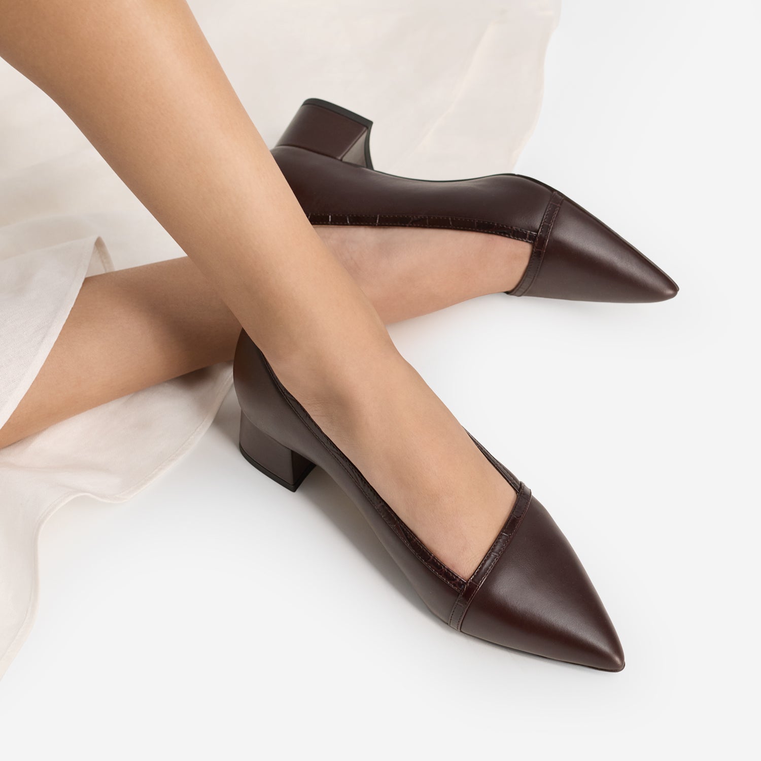 Brown pointed-toe shoes worn by a person on a white background
