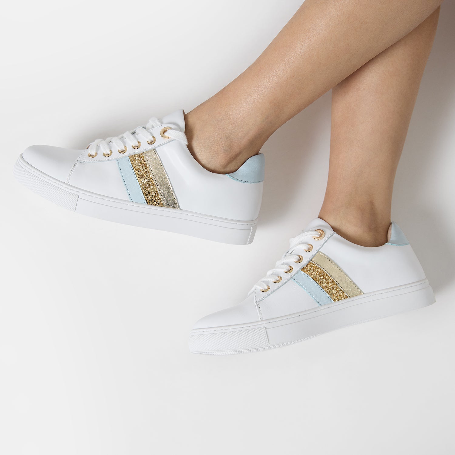 Sneaker worn by model features white leather upper, gold hardware, glitter and powder blue accents. 