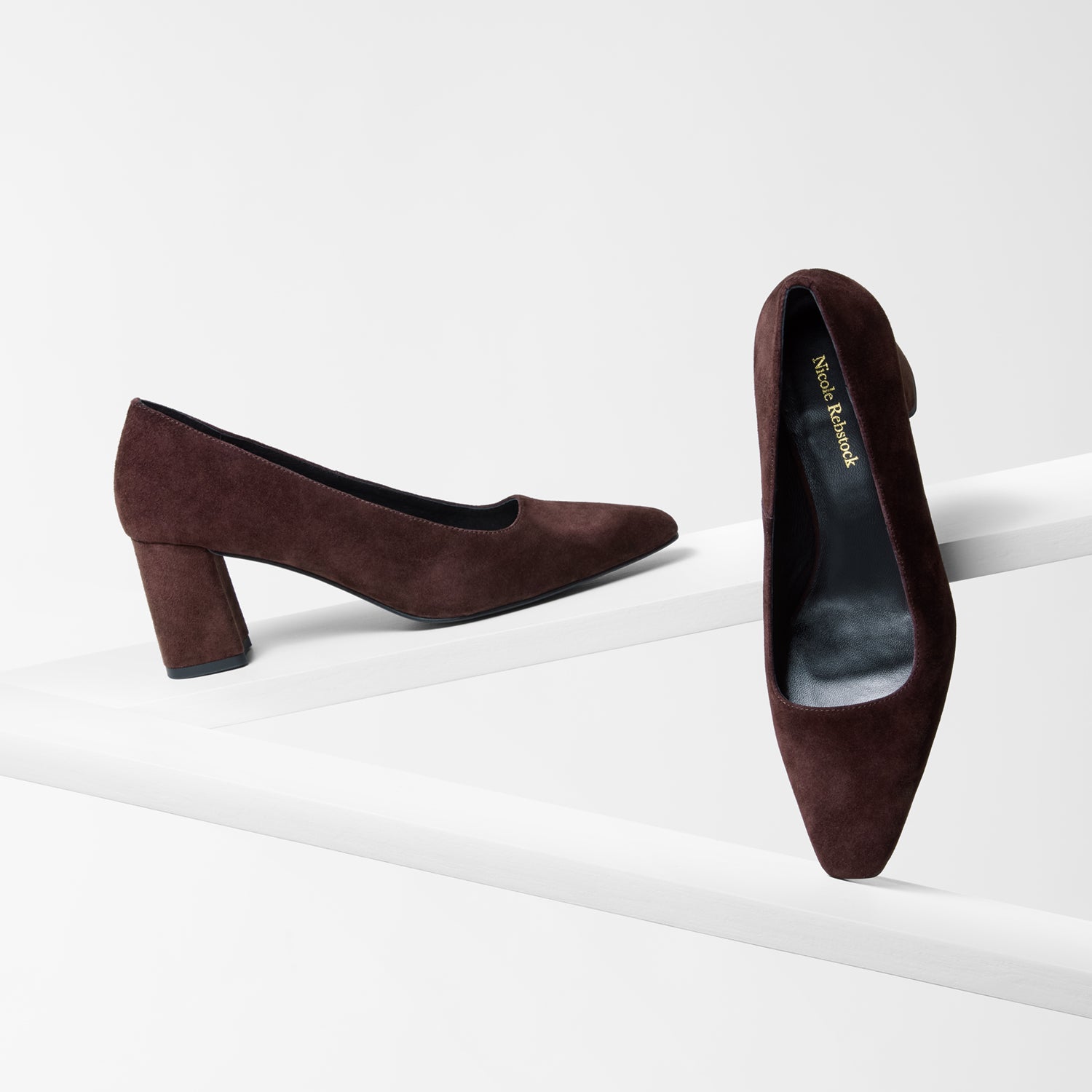 Pair of brown suede heels with a square toe on a white background