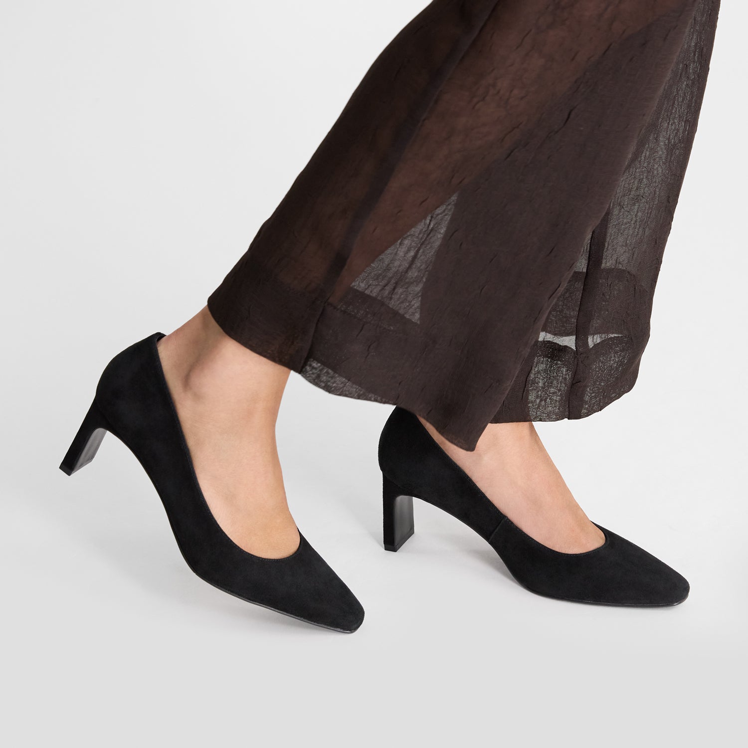 Black suede leather pumps by Nicole Rebstock, worn by a model.