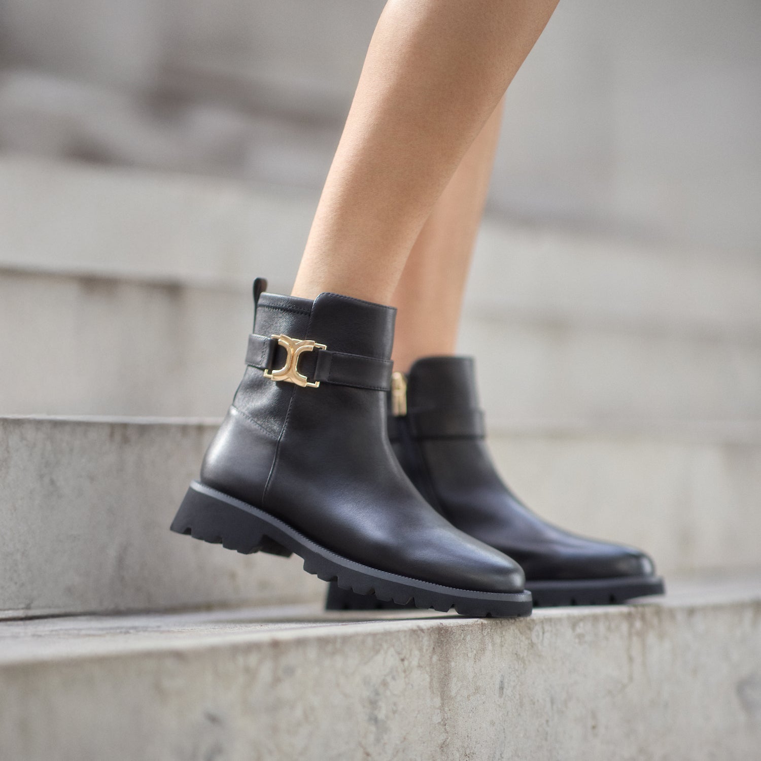Black leather boots with gold buckle and treaded sole.