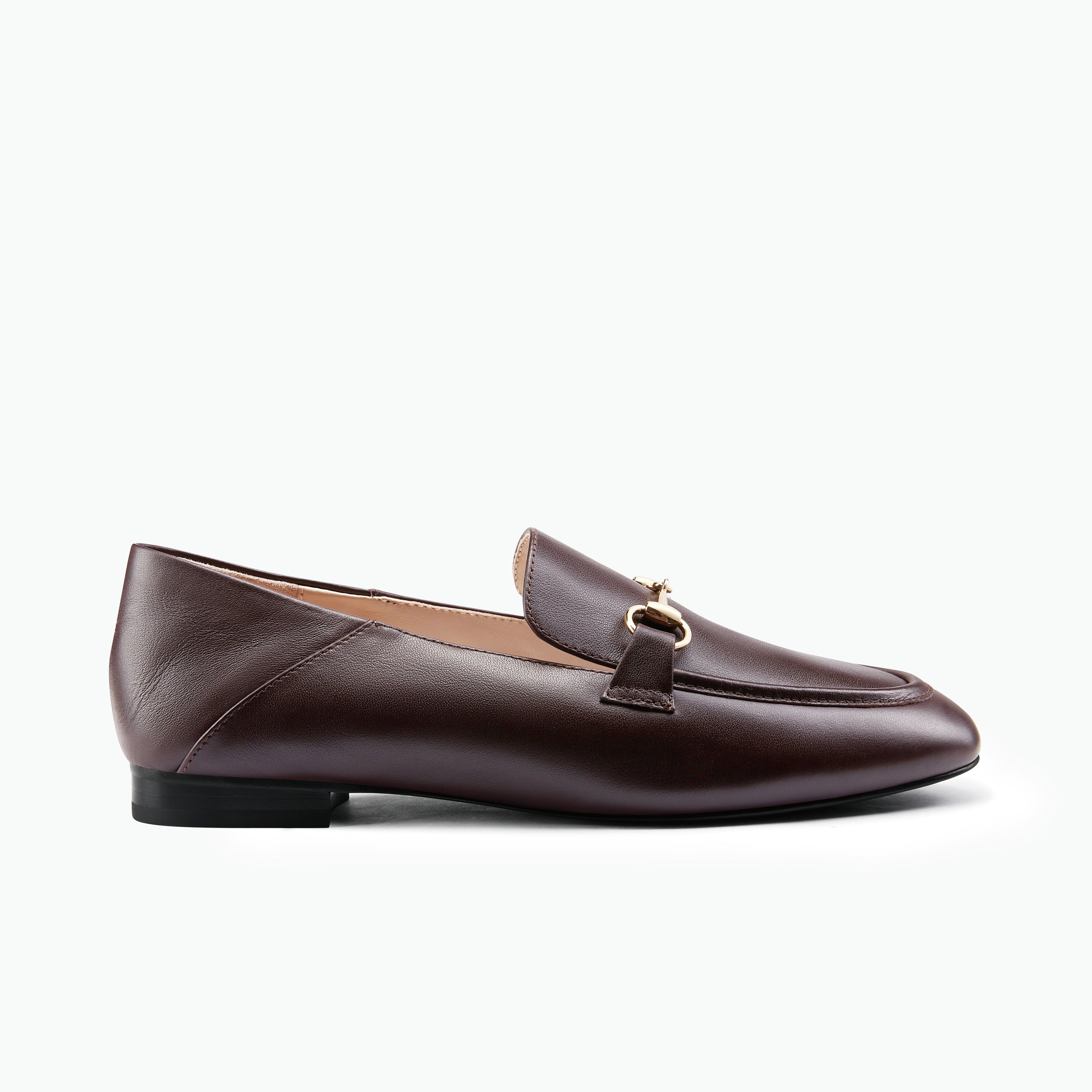 A dark brown leather loafer with a gold-tone horsebit detail on the strap, shown in a side profile against a clean white background.