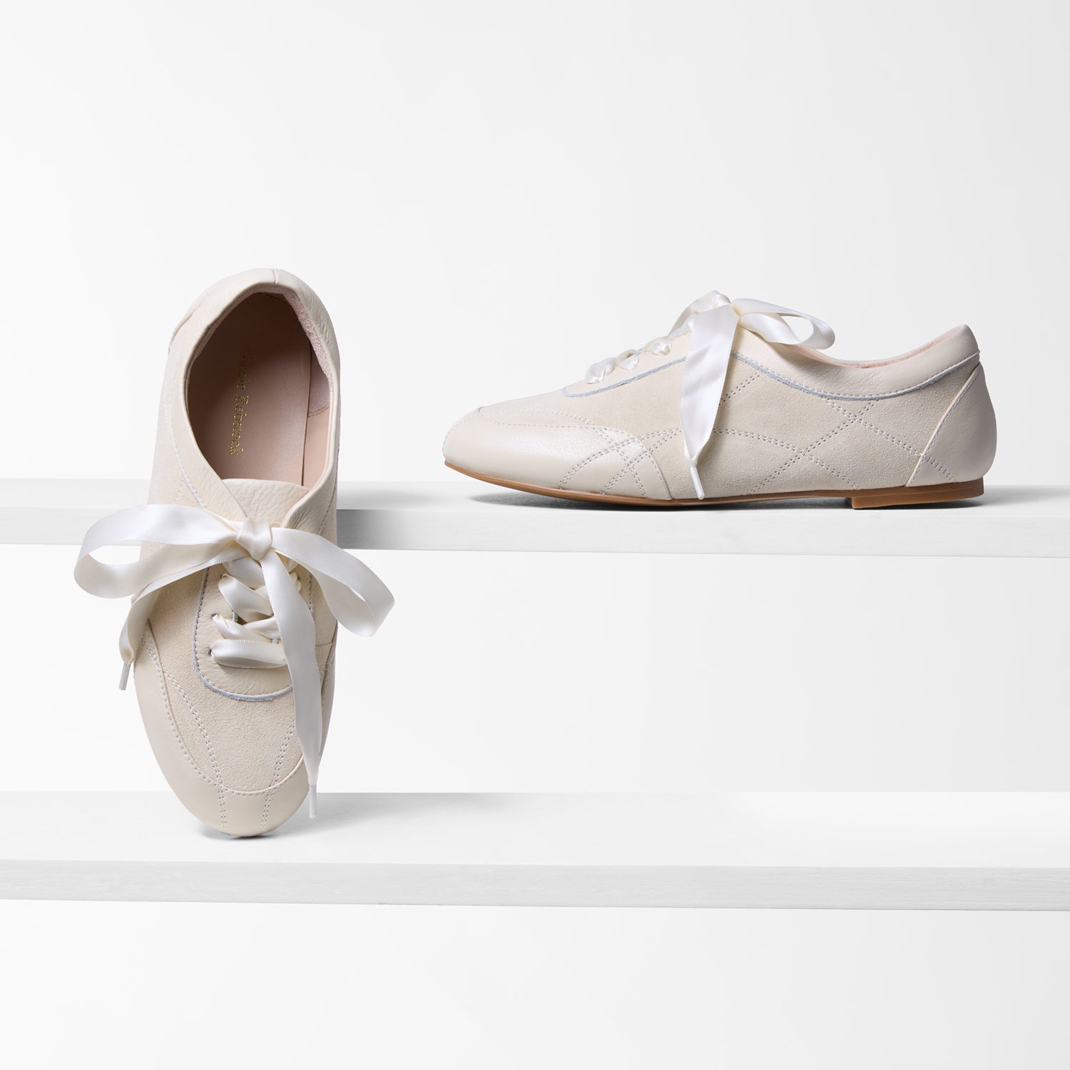Pair of oat sneakerinas with ribbons on a white background