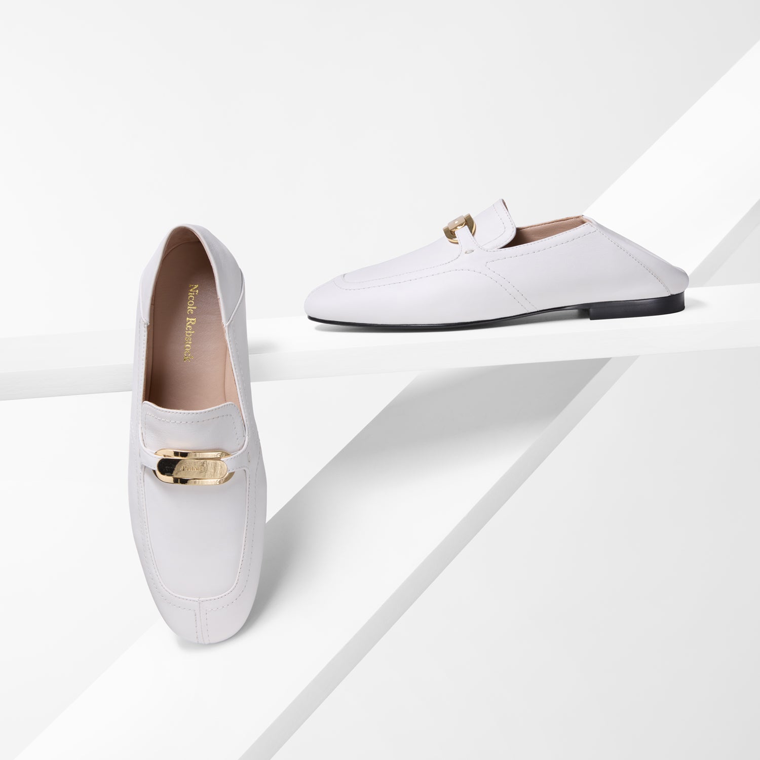 White loafers with gold buckles on a white background