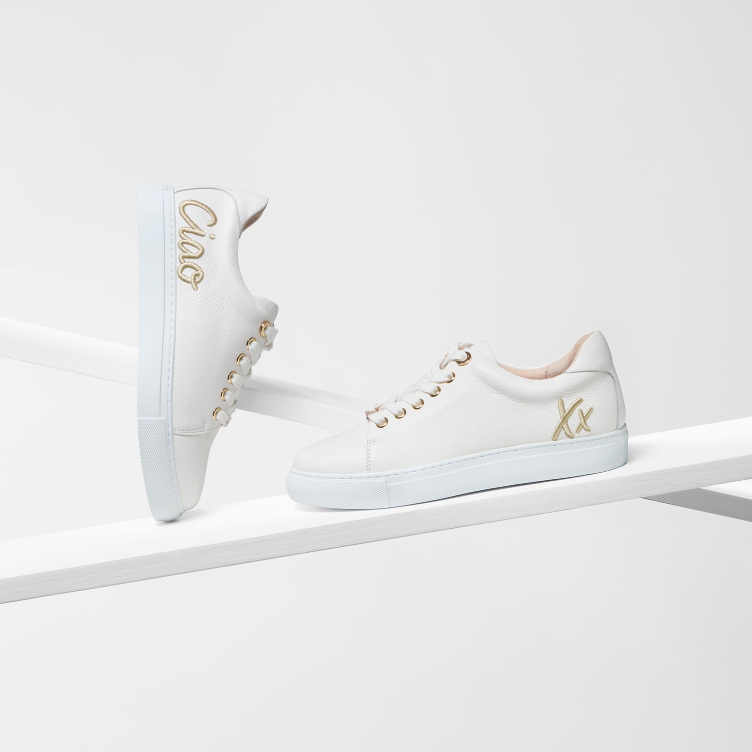 White pebble leather sneakers with gold embroidery and gold eyelets.