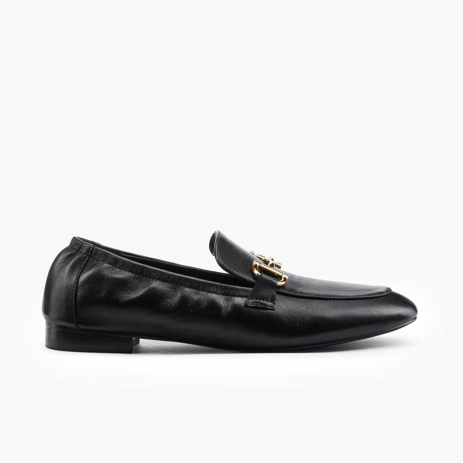 Black leather loafer with gold detail by Nicole Rebstock on a white background.