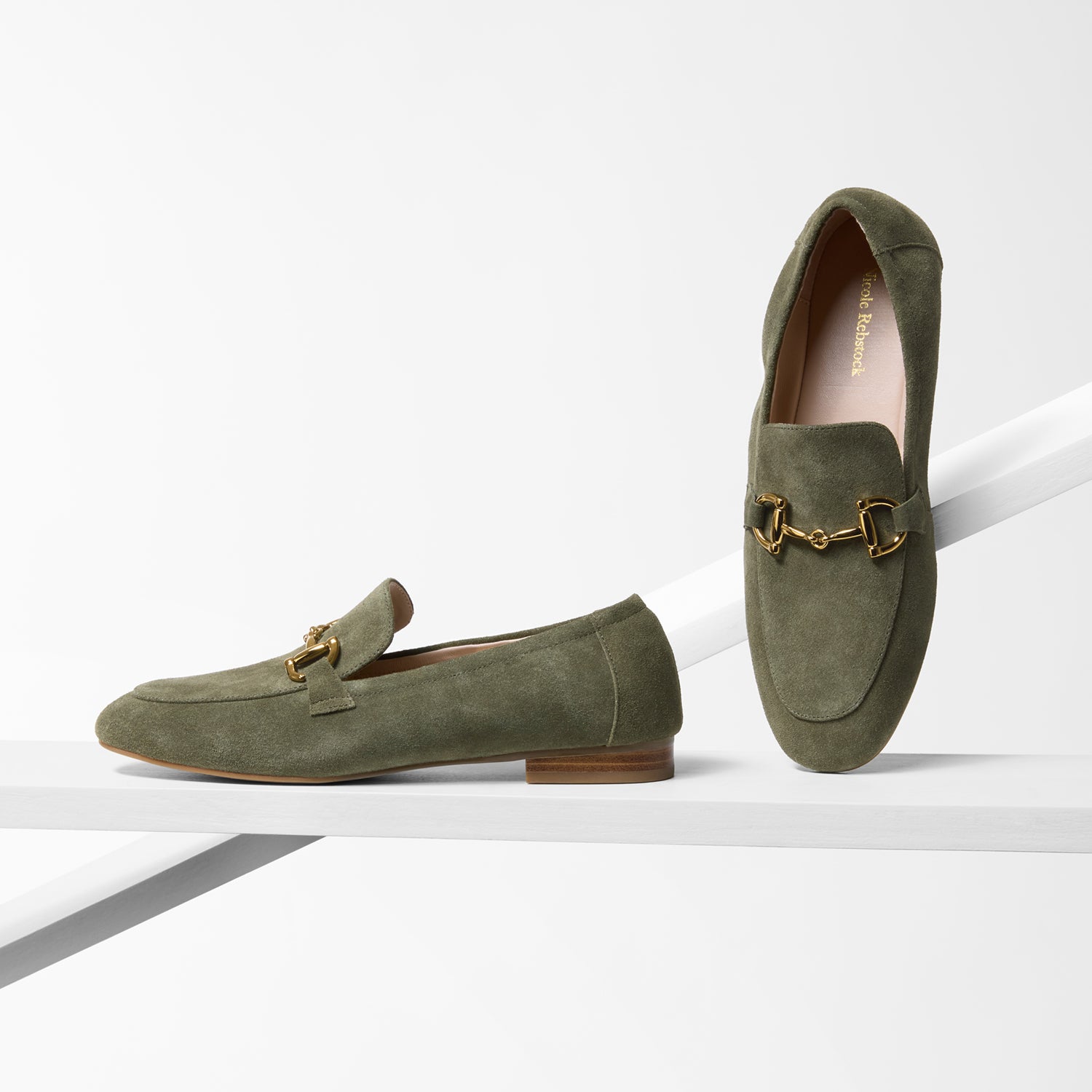 Pair of green suede loafers with gold accents on a white background