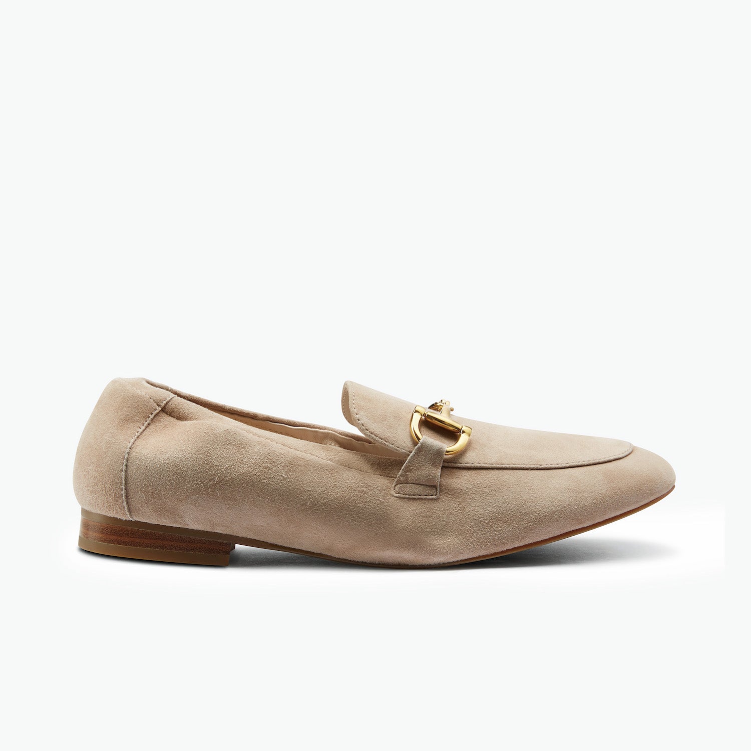 A single nude suede loafer with a gold horsebit detail on the vamp, shown in a side profile against a clean white background.