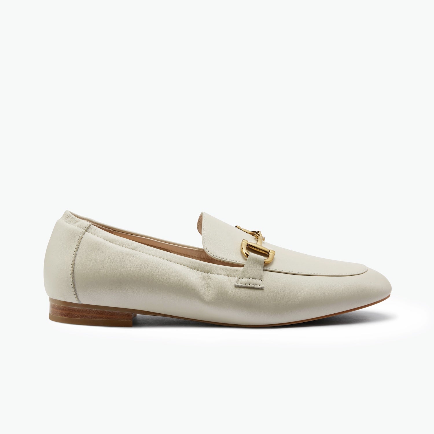 Cream loafer with gold buckle on a white background