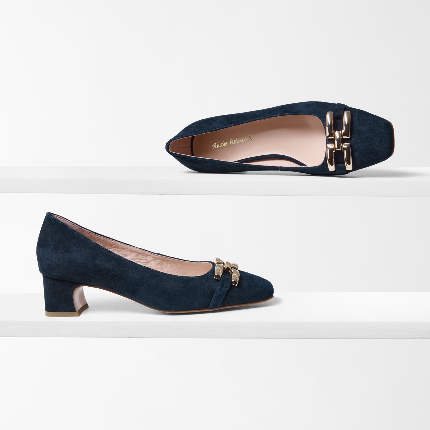 Navy blue suede shoes with gold buckles on a white background