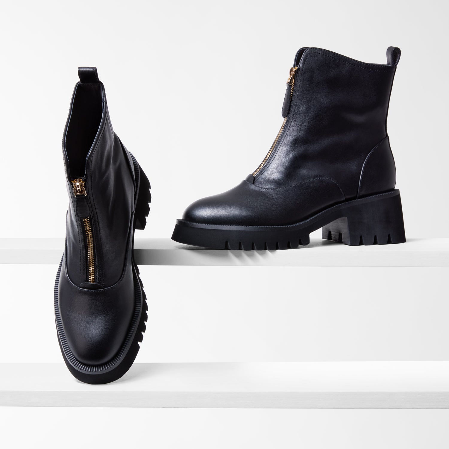 Black leather boots with gold zippers on a white background