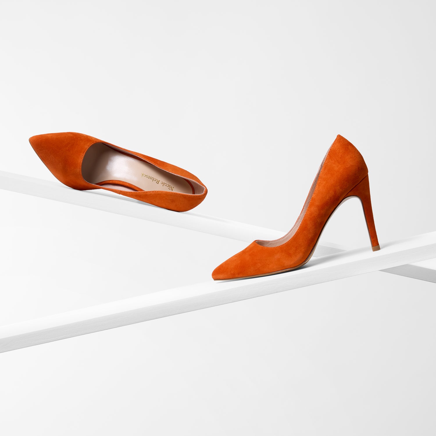 Pair of orange high-heeled shoes on a white background. Pointed toe and 9.5cm stiletto heel.