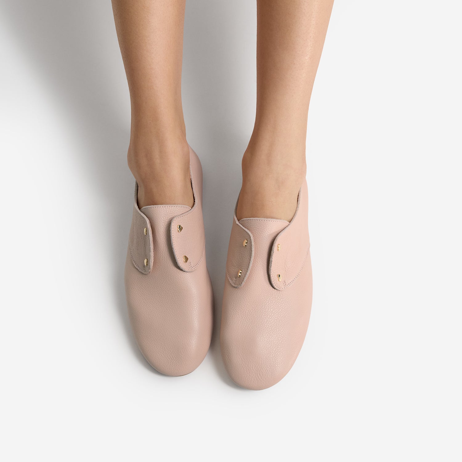 Pair of light pink flats called Xeno by Nicole Rebstock, worn by a person on a plain background. Gold accents.