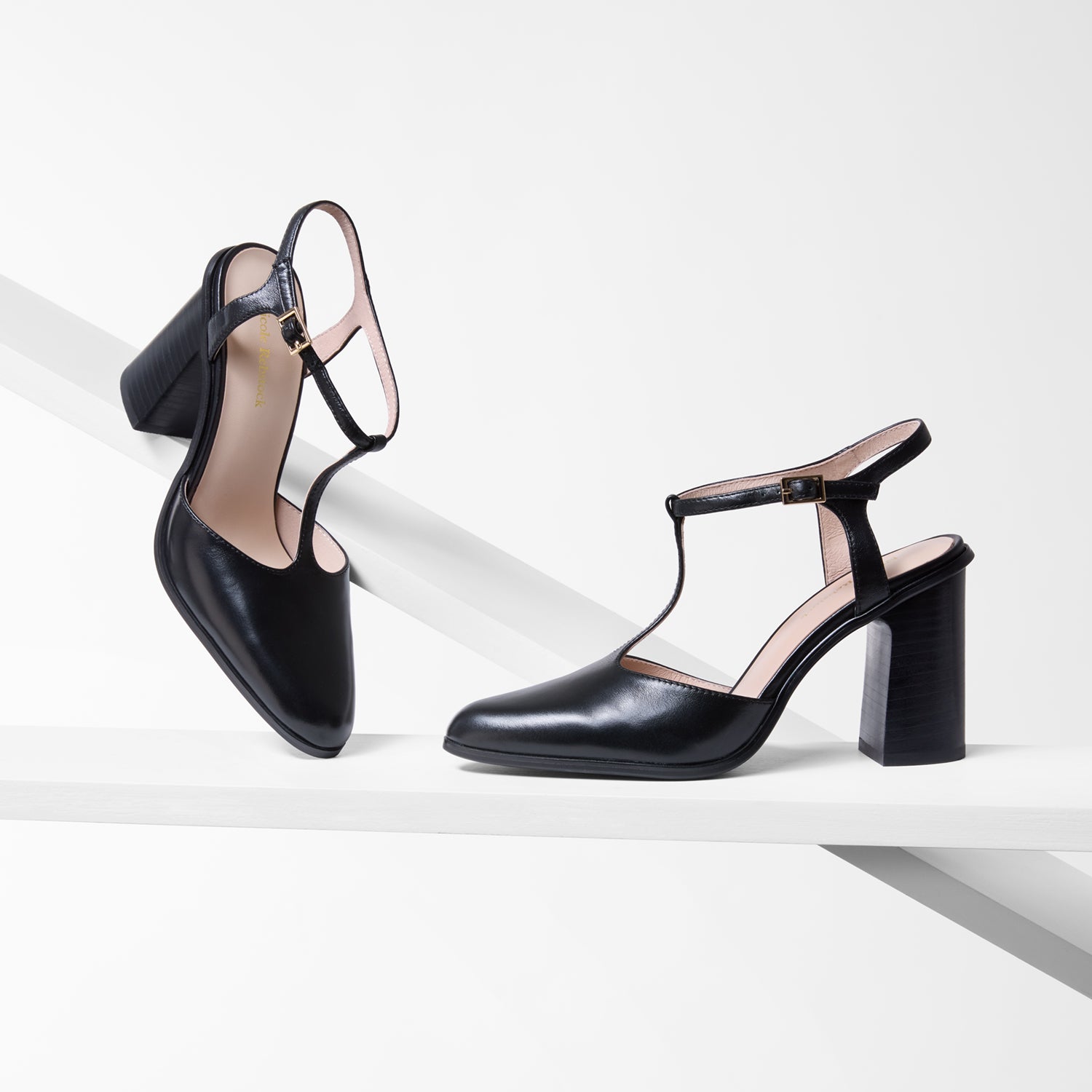 Black high-heeled shoes with thin straps on a white background