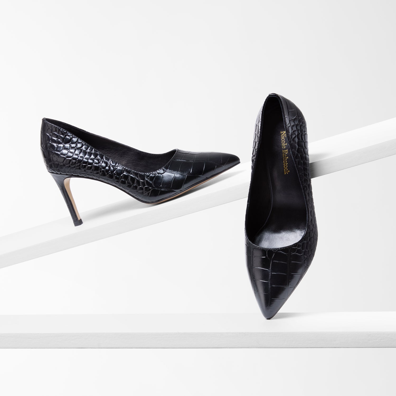 Black high-heeled shoes with crocodile texture leather on a white background