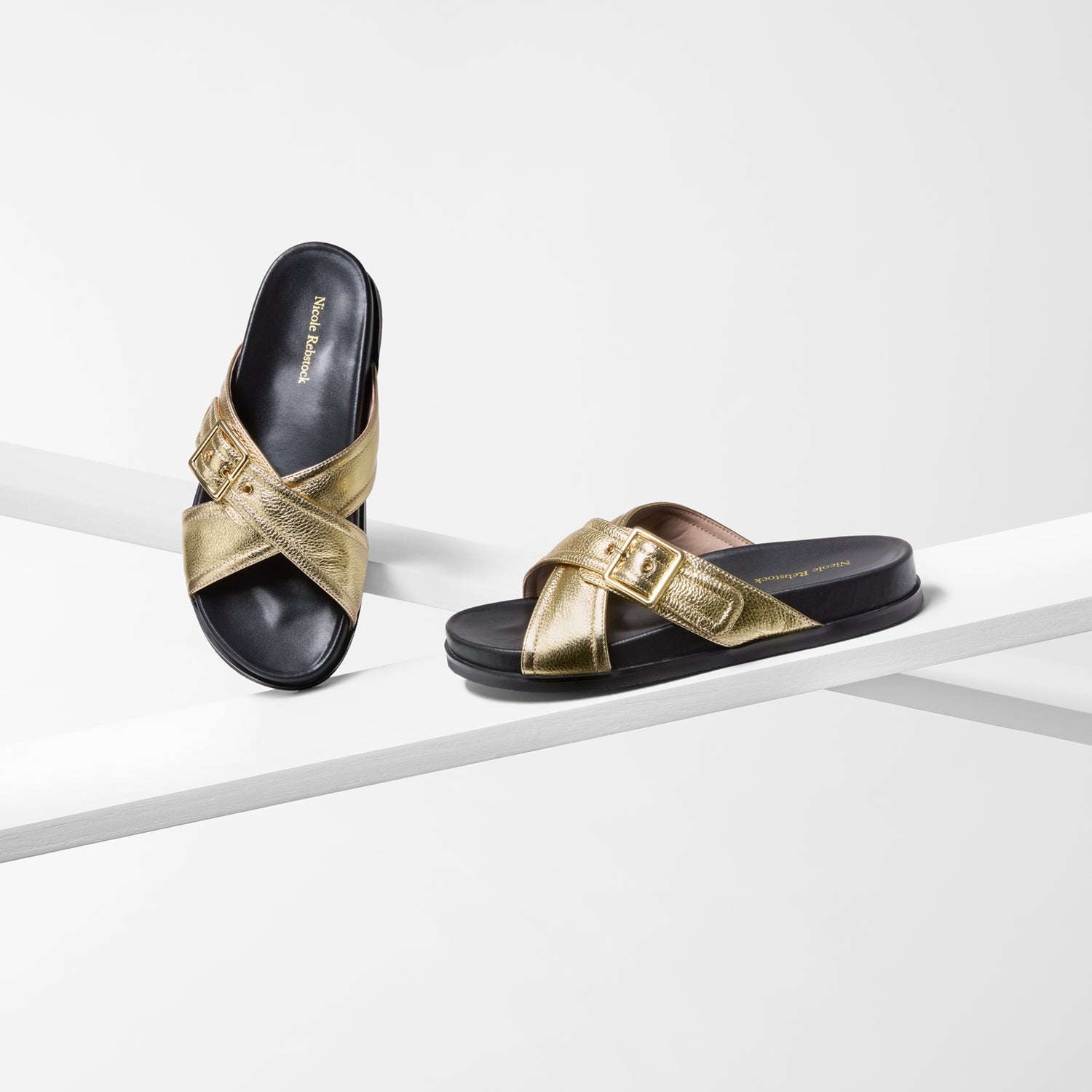Gold and black flat sandals on a white background