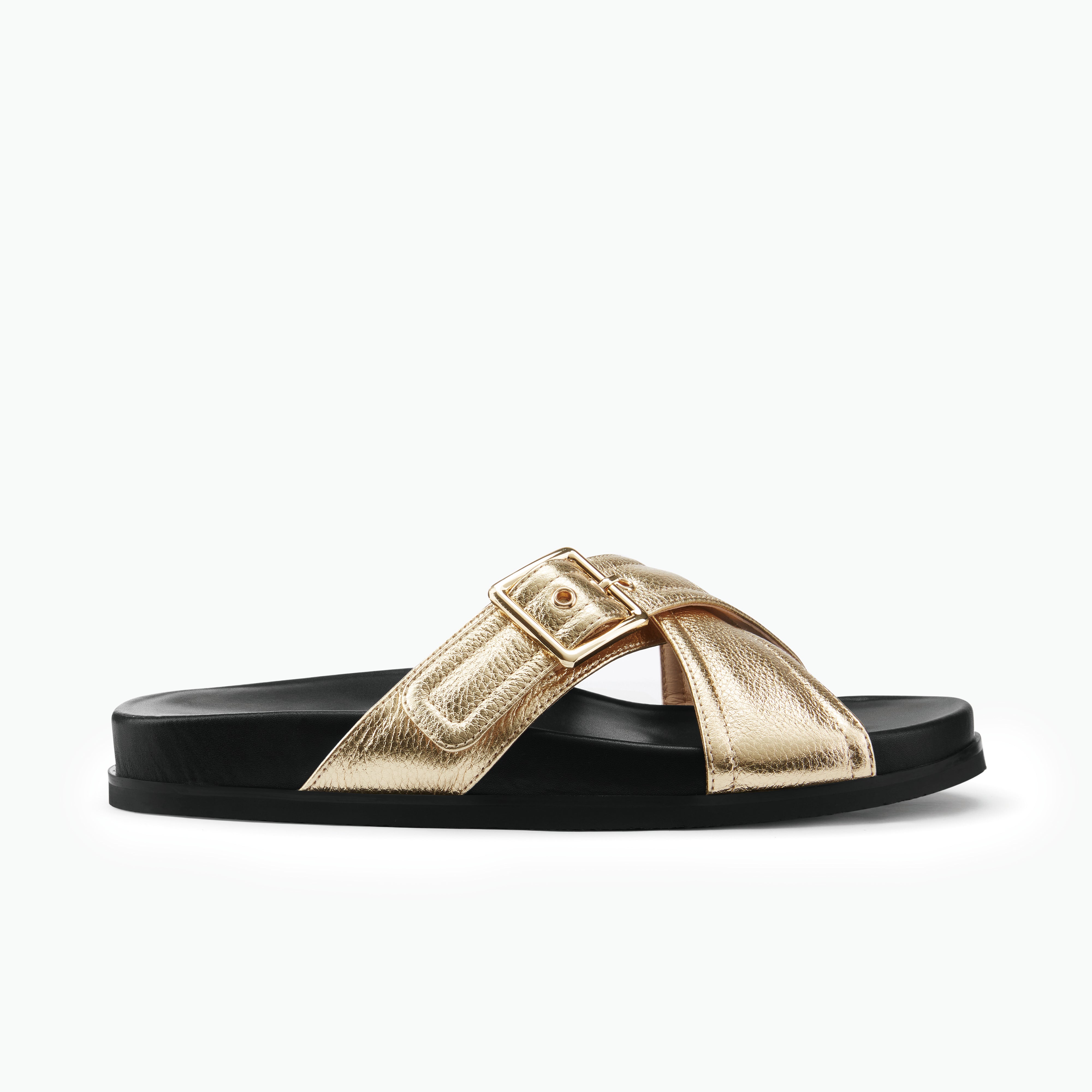 Gold slide sandal with a black sole on a white background. Made by Nicole Rebstock