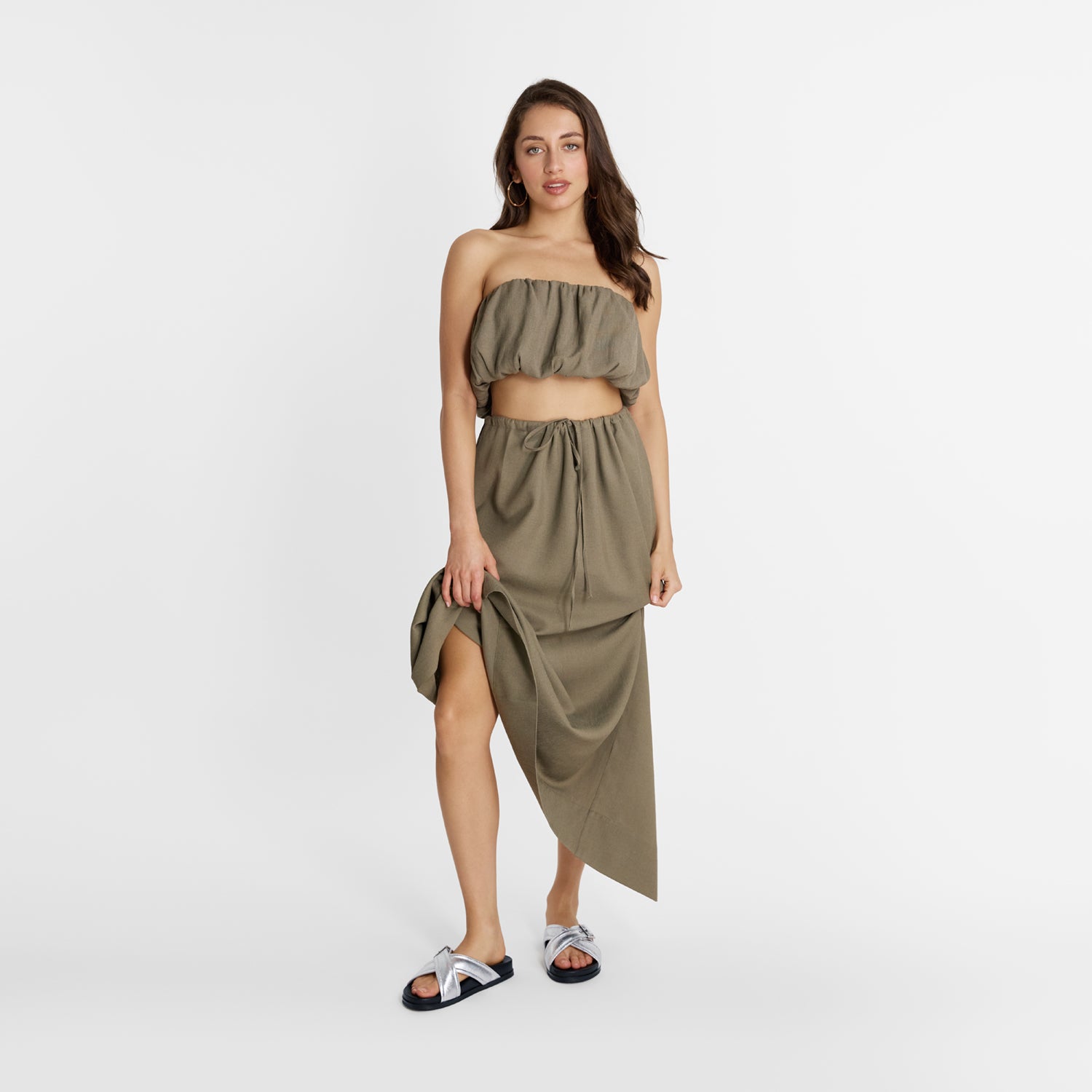 Model wearing Nicole Rebstock silver slide sandals with cross strap and silver buckle.