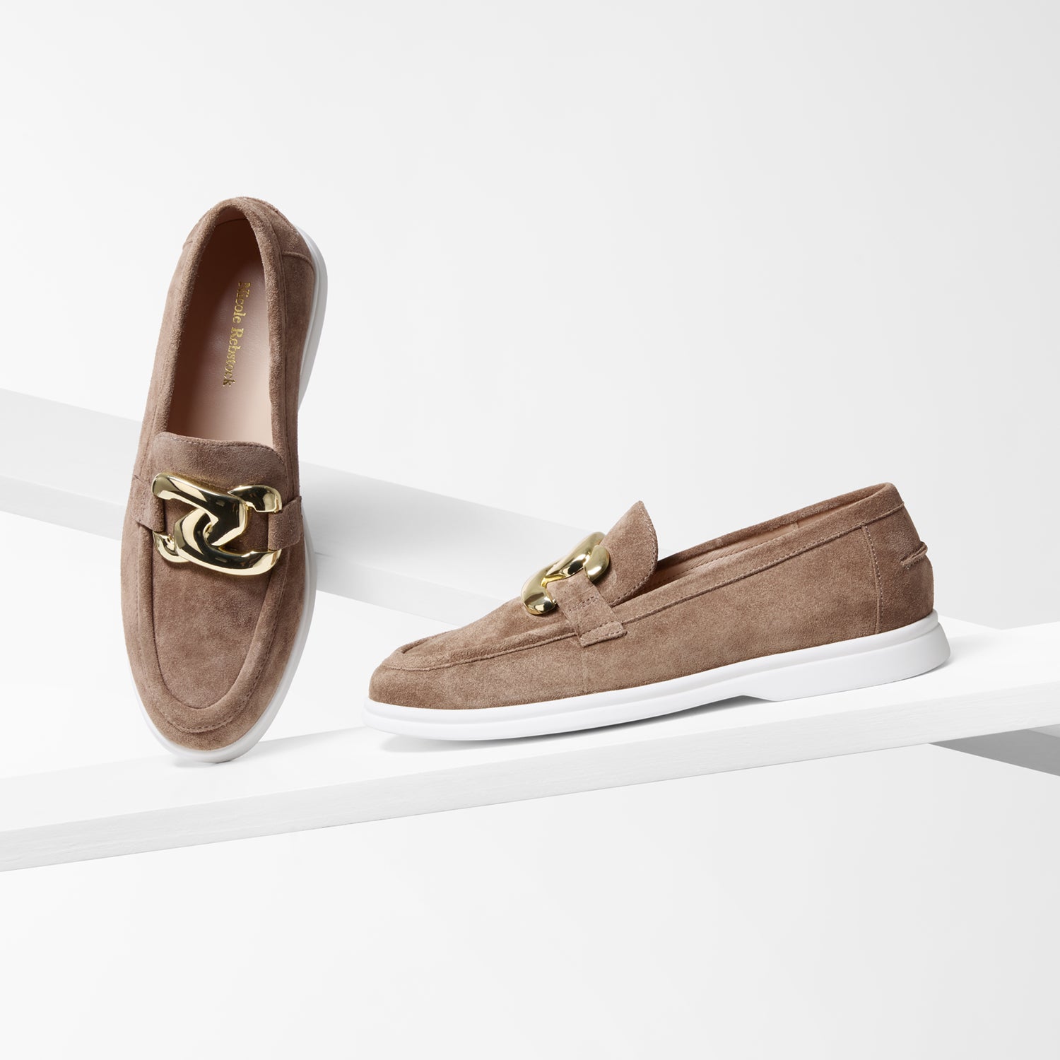 Pair of brown suede loafers with gold accents on a white background